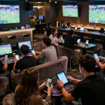 Engaged sports bettors enjoying the excitement of tỷ lệ kèo nhà cái 5 in a lively sports lounge.